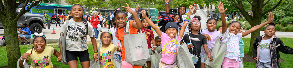 group of children smiling outside and holding bags