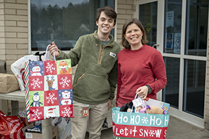 two people holding holiday gift bags