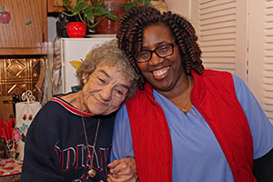elderly woman smiling and leaning against a woman