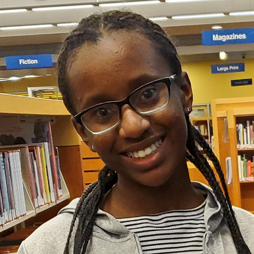 young woman standing in a library and smiling