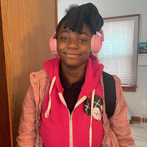 young woman smiling and wearing a pink jacket and pink headphones