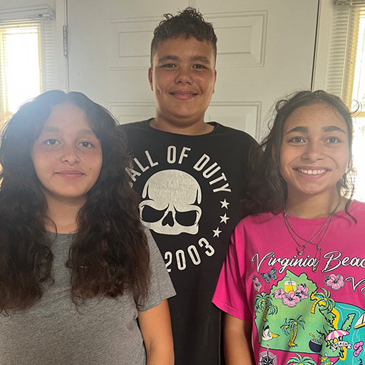 two girls and a boy standing together and smiling