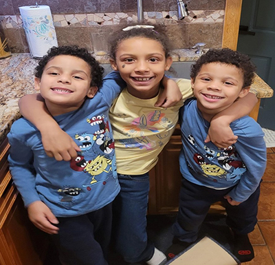 3 siblings smiling with arms around each other