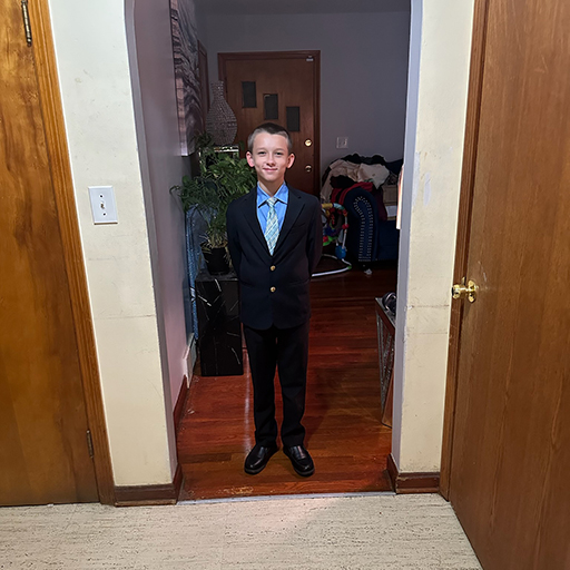 young man in a suit standing and smiling in a doorway