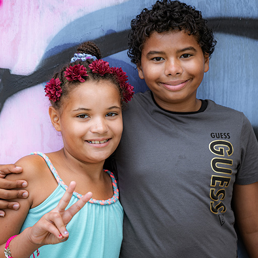 brother and sister smiling with his arm around her