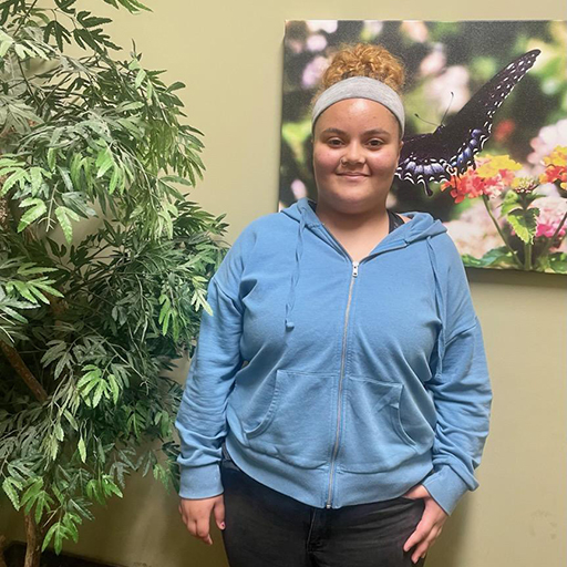 young woman standing in front of a picture of a butterfly and smiling