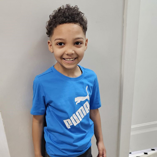 boy standing against a wall and smiling